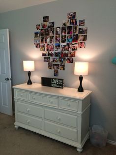 a white dresser with two lamps and pictures on the wall