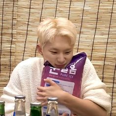 a person sitting at a table with some drinks in front of him and holding a bag