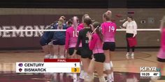 a group of women in pink shirts standing on top of a court with volleyball rackets