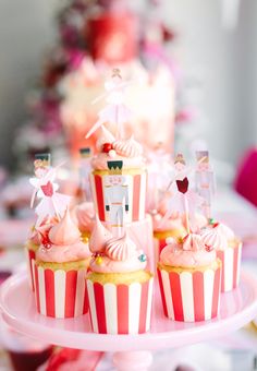 cupcakes with pink frosting and decorations on a cake stand