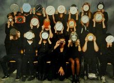 a group of people with clocks on their faces are sitting in front of each other