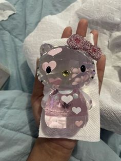 a hand holding a small clear bear with hearts on it