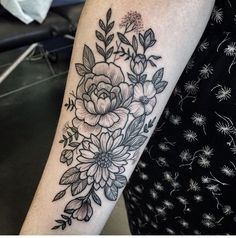 a black and white flower tattoo on the arm