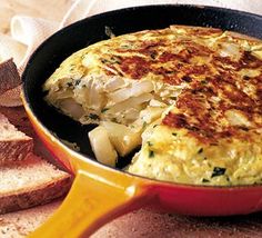 an omelet in a skillet with bread on the side and a napkin next to it