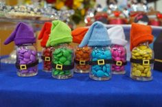 small glass jars filled with candy sitting on top of a blue table