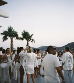 a group of people standing next to each other on top of a roof near palm trees