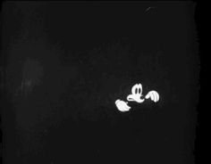 a black and white photo of mickey mouse flying through the air with his arms outstretched