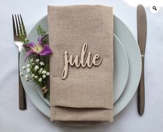 a plate with a napkin that says julia on it next to a fork and knife