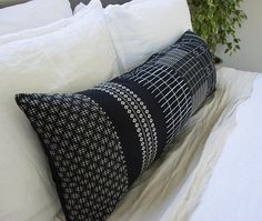 a black and white pillow sitting on top of a bed next to a potted plant