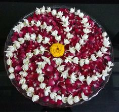 a bowl filled with red and white flowers on top of a black countertop next to a yellow button