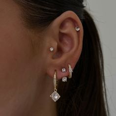 a close up of a person wearing ear rings with diamond earrings on top of them