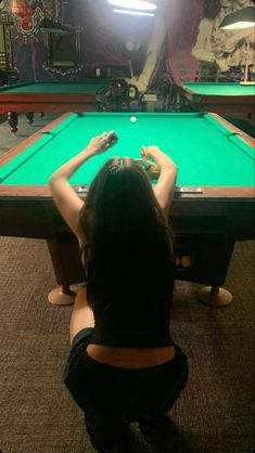 a woman is sitting at a pool table