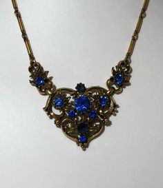 Signed Coro Vintage Antique Necklace SIGNED CORO Blue Rhinestone With Jewelers Brass Gold Tone Chain Jewelry app 16 inch Vintage Antique Necklace SIGNED CORO with Gold Tone Heart and Blue Rhinestones set through out has period 1940's scroll work and is in great condition. Spring Ring clasp. No missing rhinestones, great sparkle and shiny gold tone Jewelers Bronze Base Metal Over all is in excellent condition Shipped first class free 2-5 days Blue Jeweled Rhinestone Costume Necklace, Blue Rhinestone Necklaces For Evening, Blue Rhinestone Necklace For Evening, Vintage Blue Jeweled Necklaces, Vintage Blue Jewelry With Chain, Vintage Blue Chain Jewelry, Vintage Blue Necklace For Evening, Formal Blue Metal Necklace, Blue Jeweled Metal Necklaces