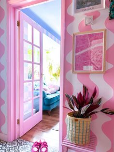 a room with pink and white wallpaper has a potted plant next to the door