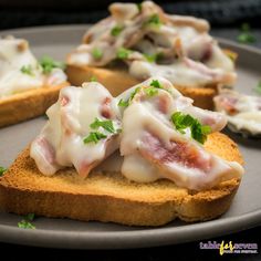 two pieces of bread with meat and cheese on them, sitting on a gray plate