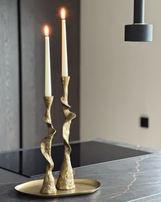 two candles sitting on top of a table next to each other with one candle in the middle