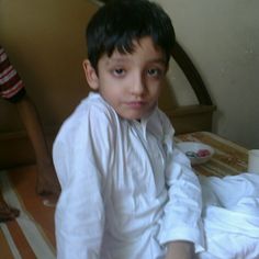 a young boy sitting on top of a bed