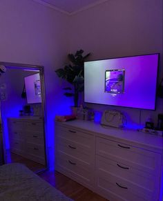 a bedroom scene with focus on the tv and dressers in the foreground, illuminated by blue lights