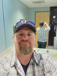 a man taking a selfie in front of a mirror with his hat and goggles on