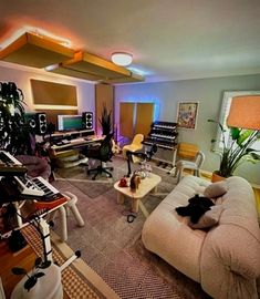 a living room filled with lots of furniture and musical equipment on top of carpeted flooring