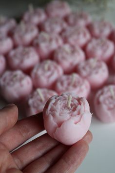 a hand is holding a small pink dessert