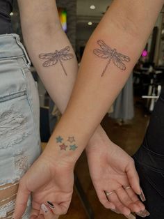 two people holding hands with tattoos on their arms