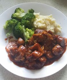 a white plate topped with meat covered in gravy and broccoli