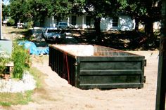 there is a large container sitting in the middle of a yard with cars parked behind it