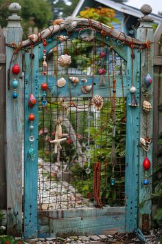 an old blue gate with shells and beads on it's sides is surrounded by greenery