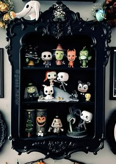 there are many halloween figurines on this black china cabinet in the living room