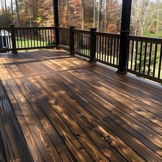 a wooden deck with railings and trees in the background