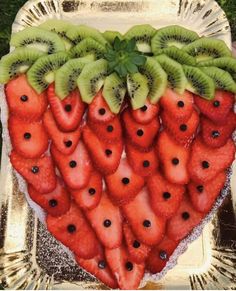 a heart shaped fruit platter with kiwis and strawberries on it