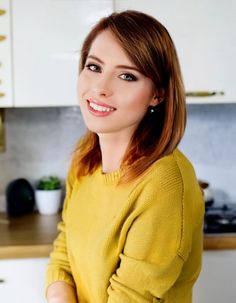 a woman in a yellow sweater is smiling at the camera