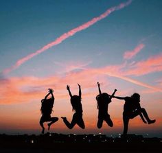 three girls jumping in the air at sunset