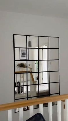 a mirror that is on the side of a stair case in a room with white walls and wooden handrails