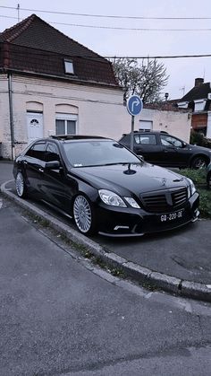 a black car is parked on the side of the road in front of a building