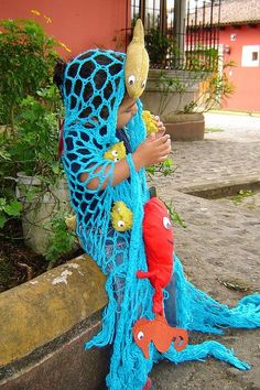 an image of a person dressed as a fish and wearing a blue crochet shawl