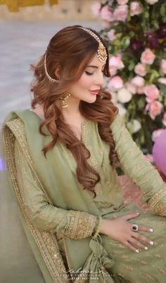 a woman sitting on top of a couch wearing a green dress and headpieces