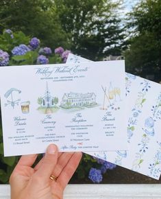 someone is holding up some cards in front of purple and blue flowers on the window sill