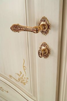 an ornately decorated white cabinet with gold handles and knobs on the front door