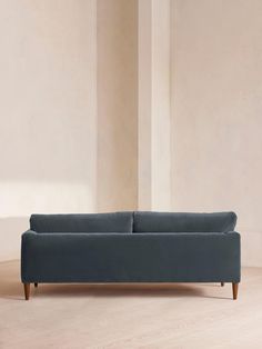 a blue couch sitting on top of a hard wood floor next to a white wall