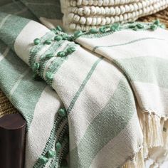 a green and white plaid blanket sitting on top of a wooden table next to a vase