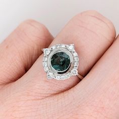 Make a statement with this unique Blue Green Indicolite Tourmaline Ring. The dazzling blue-green stone is complemented by a natural diamond halo, set in 14K white gold for a minimalist yet eye-catching look. Elevate any outfit with this one-of-a-kind statement piece. This ring is made with solid 14k gold and natural earth mined SI G/H diamonds. As listed, this ring is ready to ship. If you're interested in purchasing this setting with a different center stone please message us! Halo Ring With May Birthstone, May Birthstone Halo Ring With Halo Setting, Emerald Halo Ring For May Birthstone, Round Tourmaline Jewelry With Halo Setting, 14k White Gold Halo Ring With Gemstone, Designer Silver Jewellery, Indicolite Tourmaline, Jewelry Showcases, Tourmaline Ring