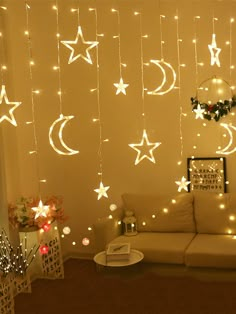 a living room decorated with stars and moon string lights hanging from the ceiling, next to a white couch