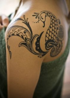 the back of a woman's shoulder with an intricate tattoo design on her arm