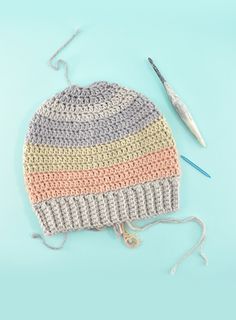 a crocheted hat with yarn next to it and a knitting needle on the side