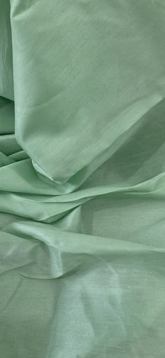 a close up view of a bed with green sheets