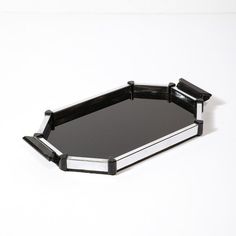 a black and silver serving tray on a white surface with the lid partially open to show it's reflection