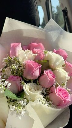 a bouquet of pink and white roses sitting in the back seat of a car