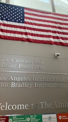 an american flag hanging from the side of a building in front of a sign that says welcome to the united states